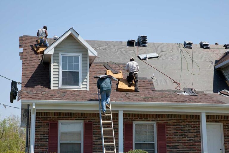 Solar panels mounted on a shingled home roof with snow on nearby roof sections.