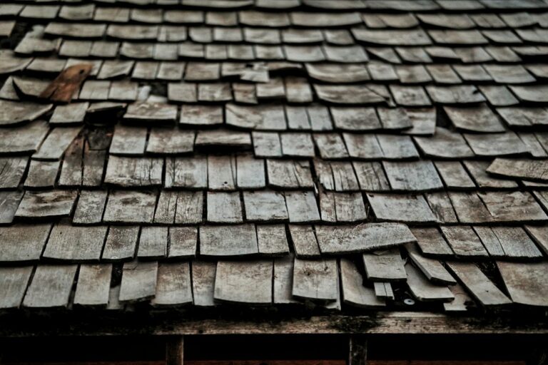 An attic view showing wood roof decking, rafters, insulation, and a small water stain near a roof penetration