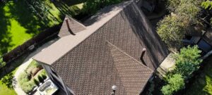 Roof shingles and attic framing showing condensation beads, damp insulation, and ventilation openings.